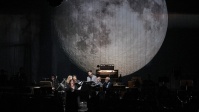 Sängerin auf Bühne mit riesigem Planeten  als Hintergrund